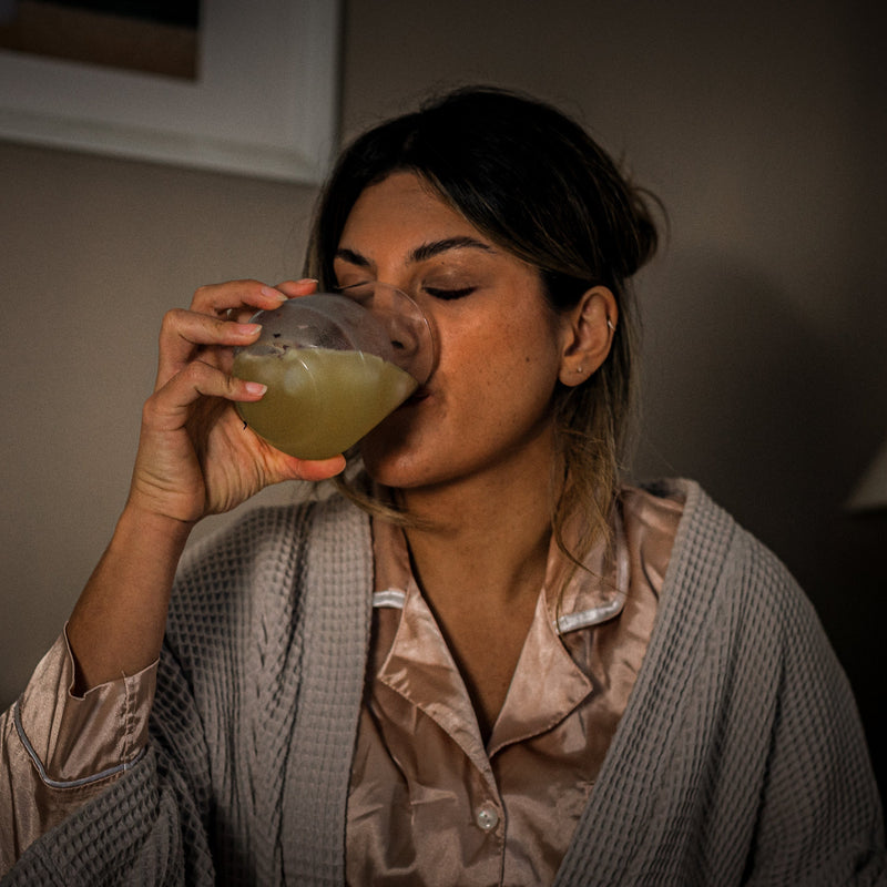A woman drinking a glass of Sleep Toniq in the evening