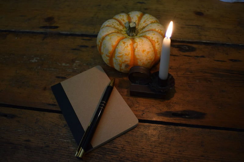 A candle and a notebook on a wooden table