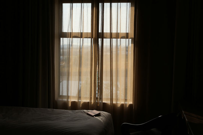 Soft morning sunlight filtering through sheer curtains into a dim, quiet room